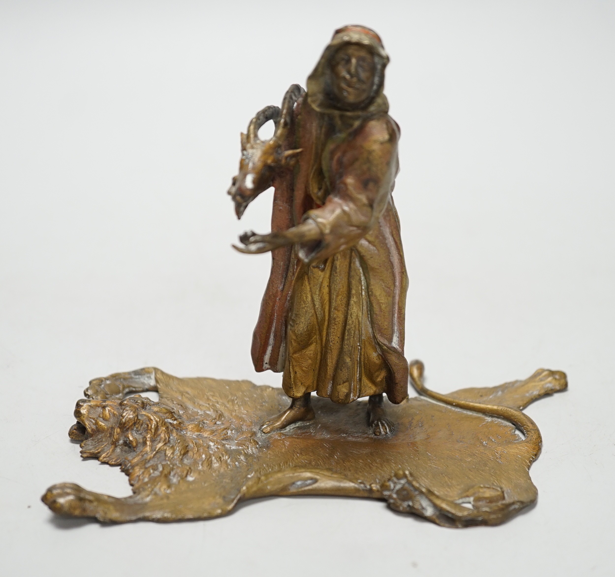 An Austrian cold painted bronze model of a Bedouin trader, depicted holding an Ibex head, standing on a lion skin, after Franz Bergman. 12cm tall